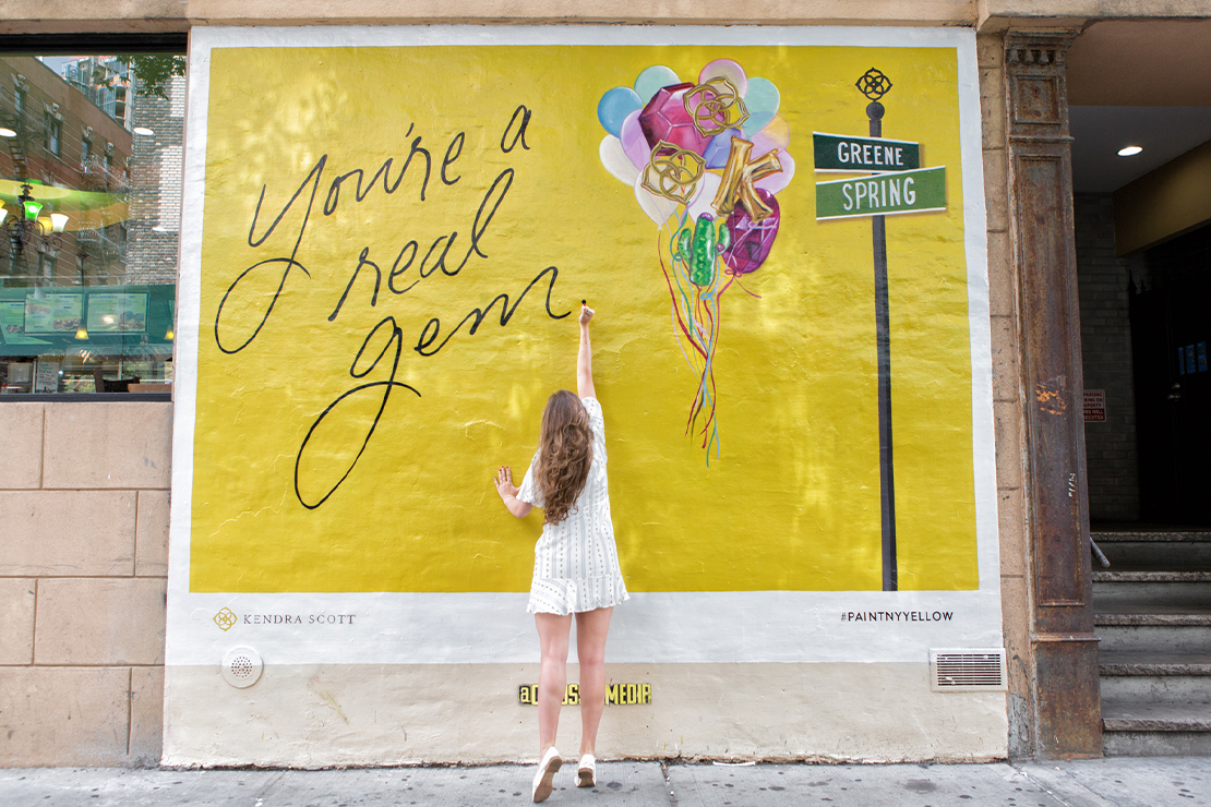 Passersby by pose in front of the Kendra Scott mural in SoHo.