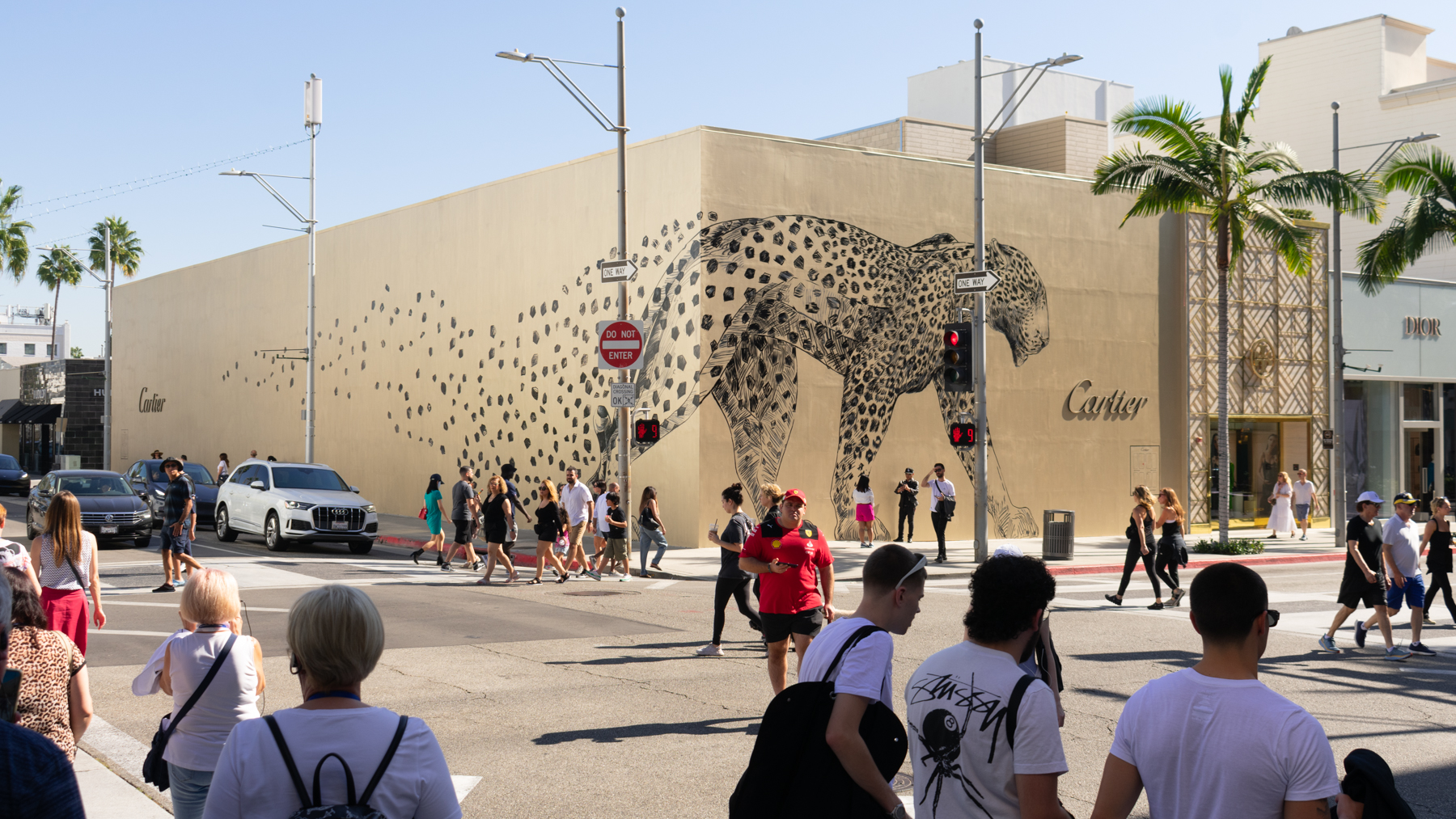 Pedestrians walking by a Colossal Media hand-painted mural of the Cartier Gold Panthère for Cartier in the City of Beverly Hills.