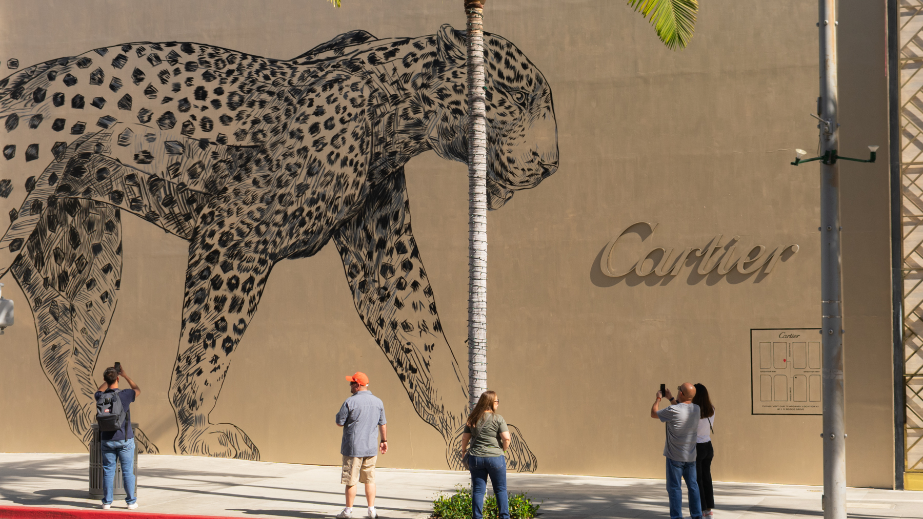 People taking photos of a Colossal Media hand-painted mural of the Cartier Gold Panthère for Cartier in the City of Beverly Hills.